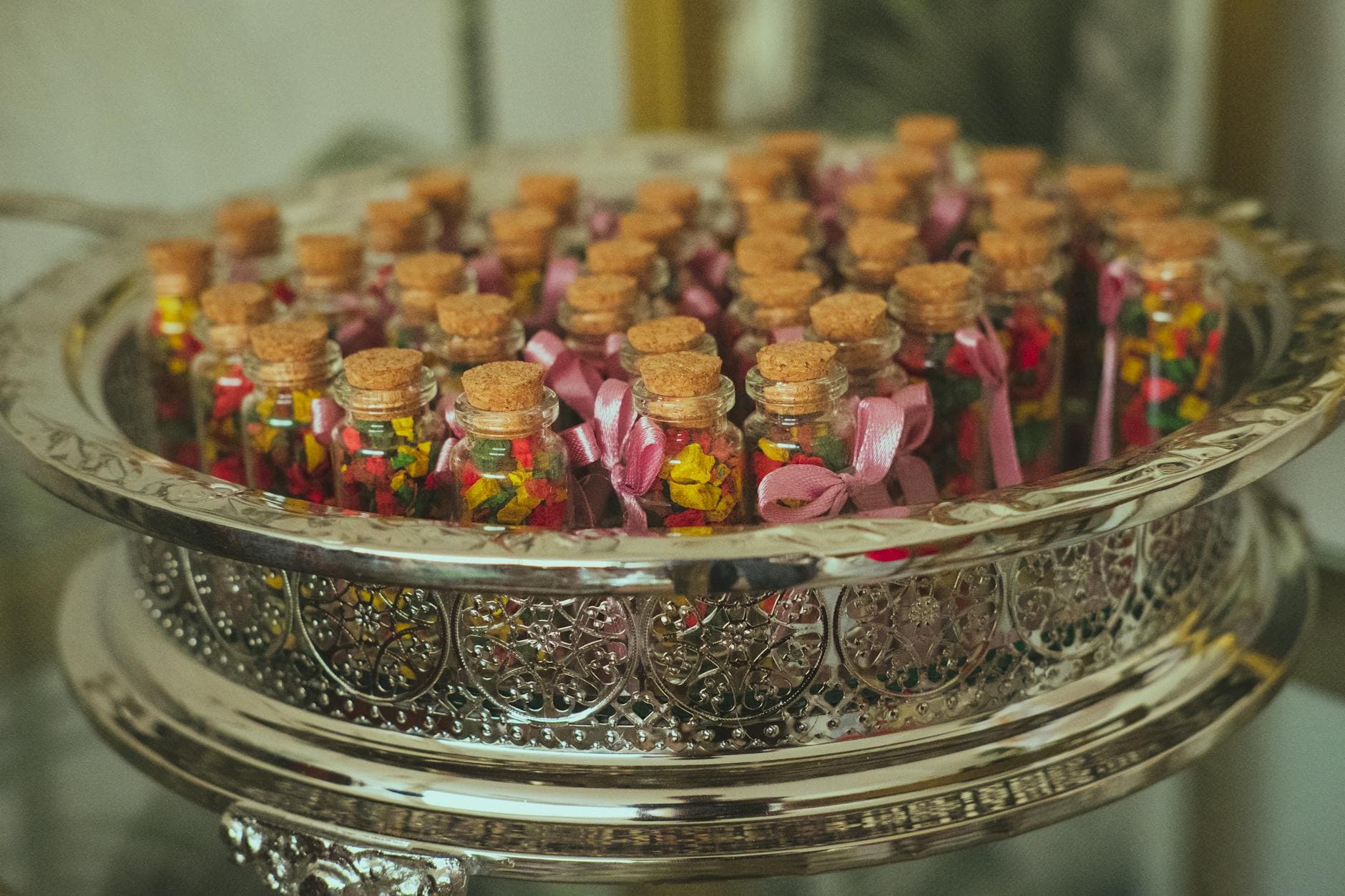Silver tray of glass favor bottles with cork stoppers and ribbons